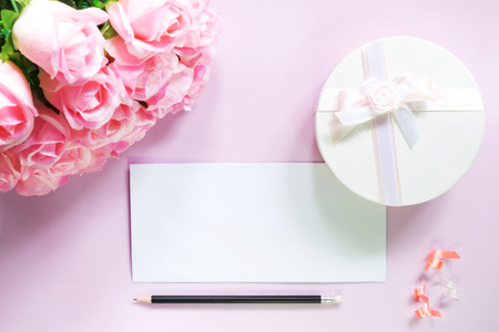 top view of flat lay decoration gift box with bow ribbon paper card / postcard and mini pin heart and rose flower with copy space on pink background, holiday valentine day love concept の写真素材