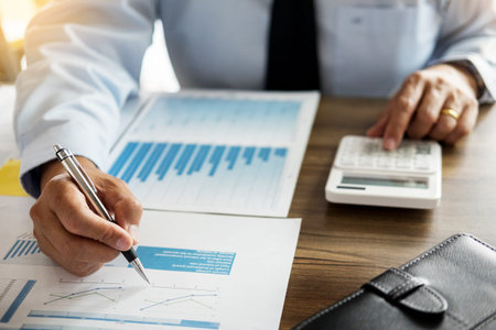 Business man working at office with laptop, tablet and graph data documents on his desk.の写真素材