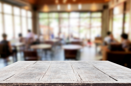 Selected focus empty brown wooden table and Coffee shop or restaurant blur background with bokeh image. for your photomontage or product displayの写真素材