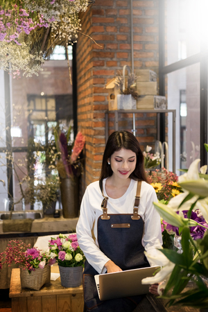 Women florist looking laptop got order at counter of her flower shop, occupation working conceptの写真素材