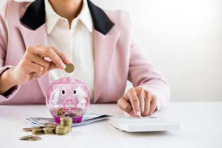 Close up of Businessman putting coin into small piggy bank , The concept of saving money and investment.の写真素材