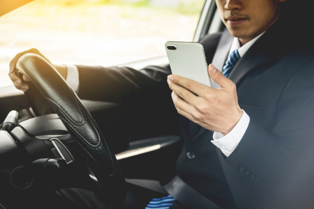 Attractive handsome young businessman using mobile smart phone in car.の写真素材