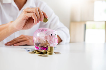 Close up of Businessman putting coin into small piggy bank , The concept of saving money and...