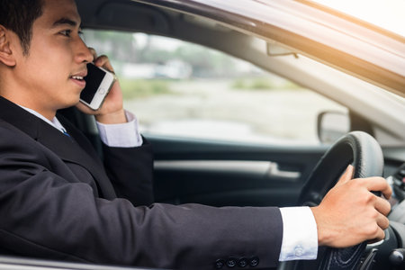Attractive handsome young businessman using mobile smart phone in car.の写真素材
