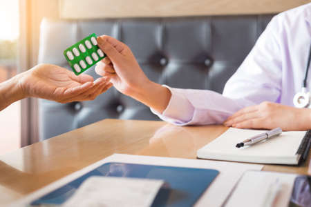 doctor hand holding tablet of drug and explain to patient in hospital room.の写真素材