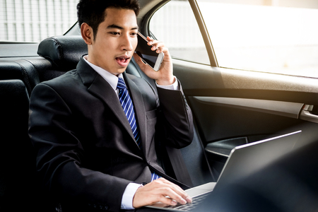 Attractive handsome young businessman using mobile smart phone in car.の写真素材