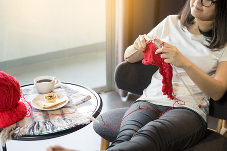 young womanâs hands knitting warm sweaters. Sitting on old armchair near window, relaxing concept in her bedroomの写真素材