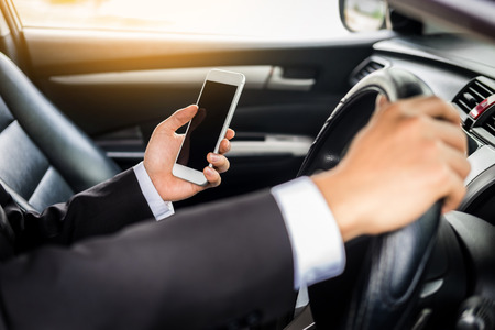 Attractive handsome young businessman using mobile smart phone in car.の写真素材