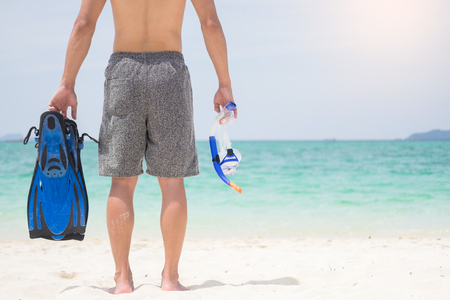 Vacation Backside of man holding snorkeling gear on tropical on the beach on summer travel destination.の写真素材