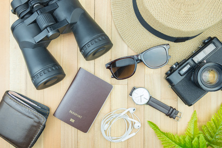 Essential traveler items accessories, tropical leaf on wood background with space. Travel vacation concept Flat lay fashion style, top view.の写真素材