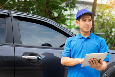 Delivery man checking document list on clipboard outdoor and Cardboard Boxes, Package delivery conceptの写真素材