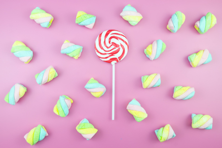 Flat lay top view tasty appetizing concept, minimal Sweet Treat Swirl Candy Lollipop marshmallow Colorful pattern on pink pastel background and copy spaceの写真素材