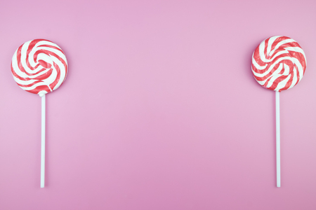 Flat lay top view tasty appetizing concept, minimal Sweet Treat Swirl Candy Lollipop marshmallow Colorful pattern on pink pastel background and copy spaceの写真素材