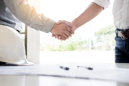 architecture and home renovation concept - builder with blueprint shaking partner hand in retro style.の写真素材