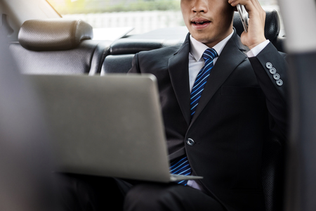 Attractive handsome young businessman using mobile smart phone in car.の写真素材