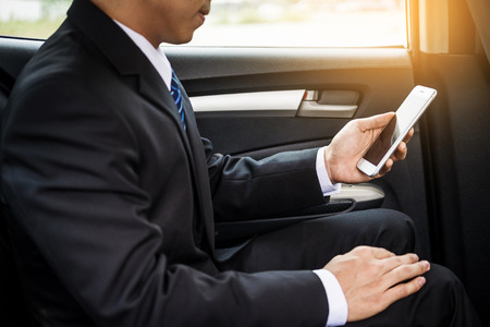 Attractive handsome young businessman using mobile smart phone in car.の写真素材