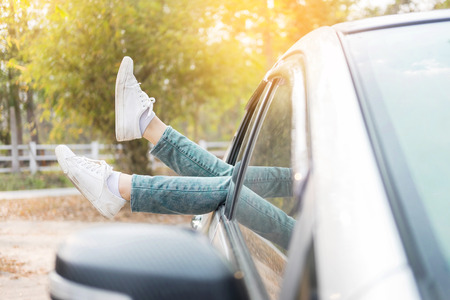 Spending weekend in roadtrip car vacation concept. Woman shoes out of car windows in car above the clouds. Conceptual freedom, travel and holidays image with copy space.の写真素材