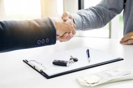 Businessman giving end key to customer after good deal agreement. while loan agreement being approved and calculator, Buy house conceptの写真素材