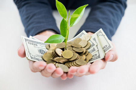 Business man hand make palm up with growing up money coins and sprout of plant savings financial concept success.の写真素材