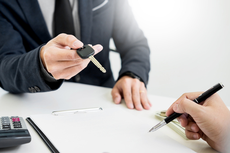 Businessman giving end key to customer after good deal agreement. while loan agreement being approved and calculator, Buy house conceptの写真素材