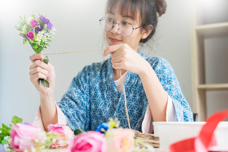 young women business owner florist making or Arranging Artificial flowers vest in her shop, craft and hand made concept.の写真素材