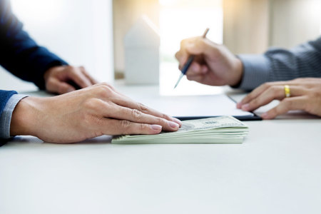 Businessman giving end key to customer after good deal agreement. while loan agreement being...
