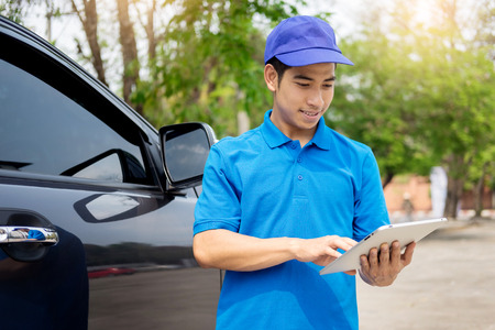 Delivery man checking document list on clipboard outdoor and Cardboard Boxes, Package delivery conceptの写真素材