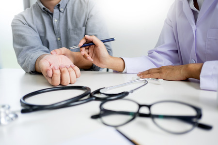 attractive Male doctor Examining discussing reports with Massage patient suffering from back pain in clinicの写真素材