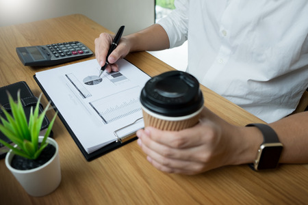 businessman going through some paperwork and signing a document at desk in officeの写真素材
