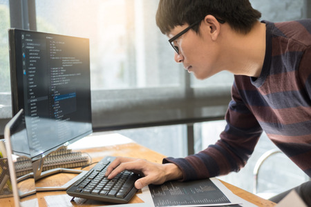Pensive programmer working on on desktop pc programming code technologies or website design at office Software Development Company.の写真素材