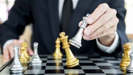 businessman playing  chess figure take a checkmate another king with team, strategy or management win or success conceptの写真素材