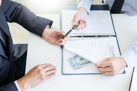 Businessman receive money in the envelope offered in file taking bribe and signing a contract - anti bribery and corruption conceptsの写真素材