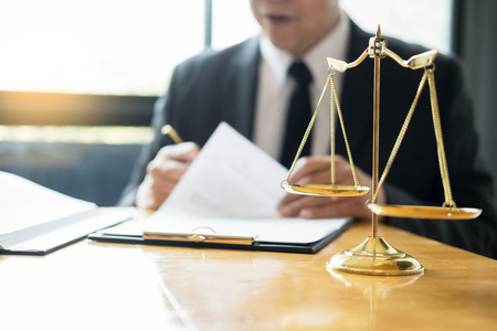 Male lawyer working with contract papers and reading law book in a courtroom, justice and law concept while presiding over trialの写真素材