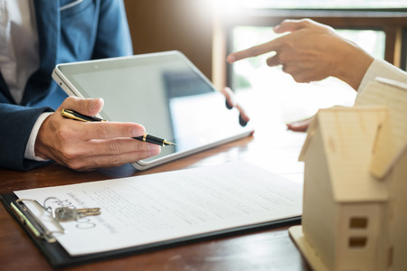 Businessman signs contract behind home architectural model
Discussion with a real estate agent rental company staffÂ 
at the office property appraisal and valuation conceptの写真素材