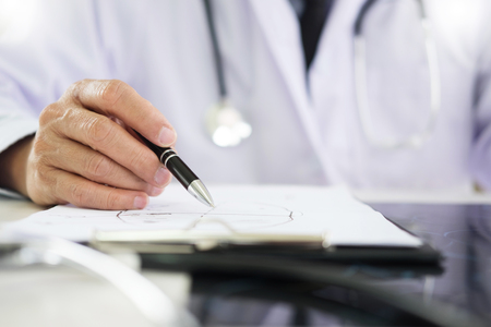 The doctor performs working writing on paperwork and analysis of the disease and the results of the patient's treatment, Healthcare and medical conceptの写真素材