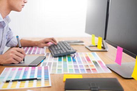 designer Editor at work drawing sketches a new project on graphic tablet and color palette sitting...