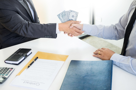 Businessman or politician taking bribe and Shaking Hands With Money in a suit, corruption trade exchange conceptの写真素材