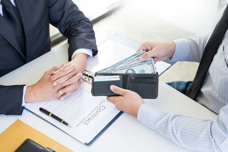 Businessman or politician taking bribe and Shaking Hands With Money in a suit, corruption trade exchange conceptの写真素材