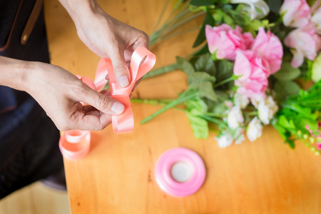 Female Florist at work using Arranging making beautiful Artificial bouquet vest at flower shop, business, sale and floristry craft and hand made conceptの写真素材