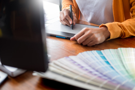 Graphic design partners working together renovation and technology concept - on a desktop computer and selection using some color swatchesの写真素材