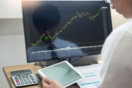 Financial broker  looking at the statistics of stock exchange and discussing on computer monitor, Business Investment Entrepreneur Trading Conceptの写真素材