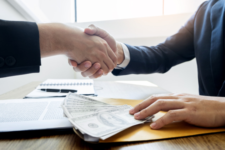 Dealing greeting and partnership meeting concept, businessmen handshaking after finishing up deal contract for both companiesの写真素材