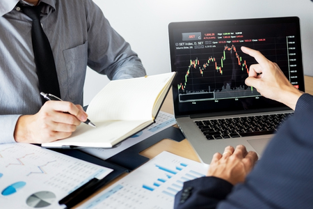 Stock traders looking at finance analysis marketing report trading stocks online in officeの写真素材