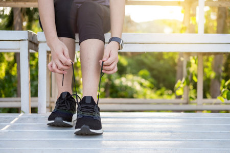 Male athlete tying shoe laces in minimalistic barefoot sneakers getting ready for training. Sport...