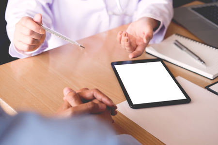 Doctor with a thermometer in his hand taking patient's in hospital, medical conceptの写真素材
