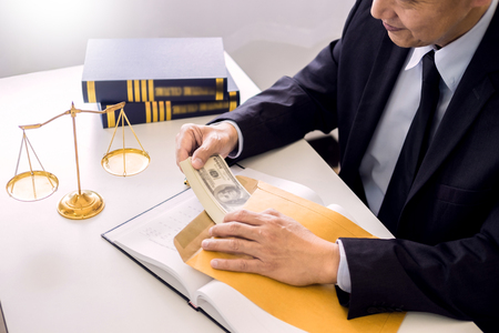 Lawyer being offered receiving money as bribe from client at desk in courtroomの写真素材