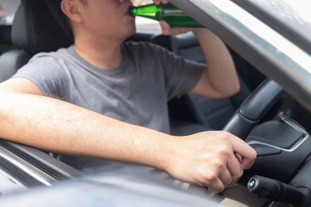 Don't Drink for Drive concept, Young Drunk man drinking bottle of beer or alcohol during driving the...