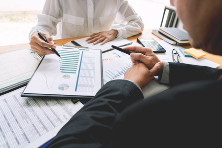 two young businessmen partner explaining information and pointing at report data discussing strategy agreement or contract at office, Teamwork, cooperationの写真素材