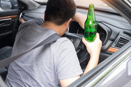 Don't Drink for Drive concept, Young Drunk man drinking bottle of beer or alcohol during driving the...
