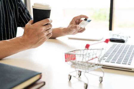 Man holding credit card in hand and entering security code using keyboard, online payment shopping concept.の写真素材
